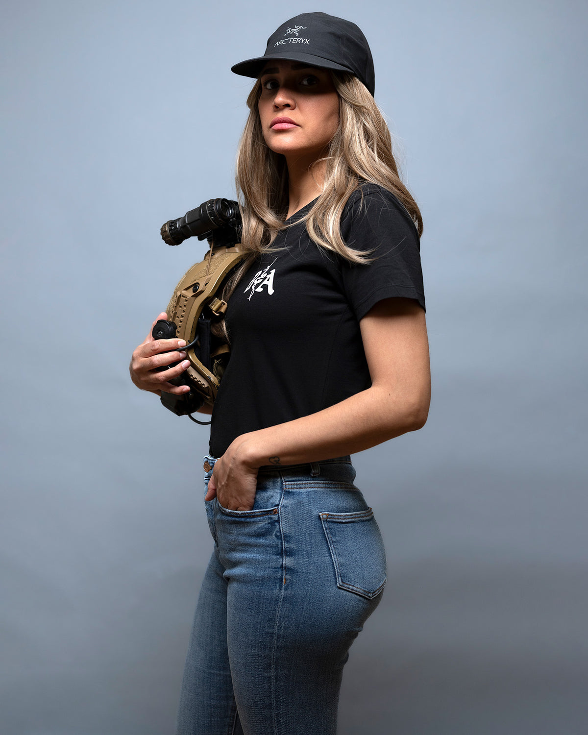 Woman in a cap wearing the black St. Michael Women's Shirt, side view