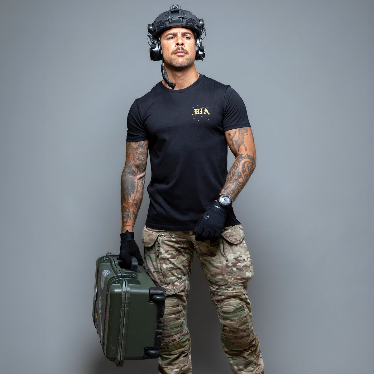 Man in a helmet and headset wearing the black Eyes On The Stars T-Shirt, holding a hard case