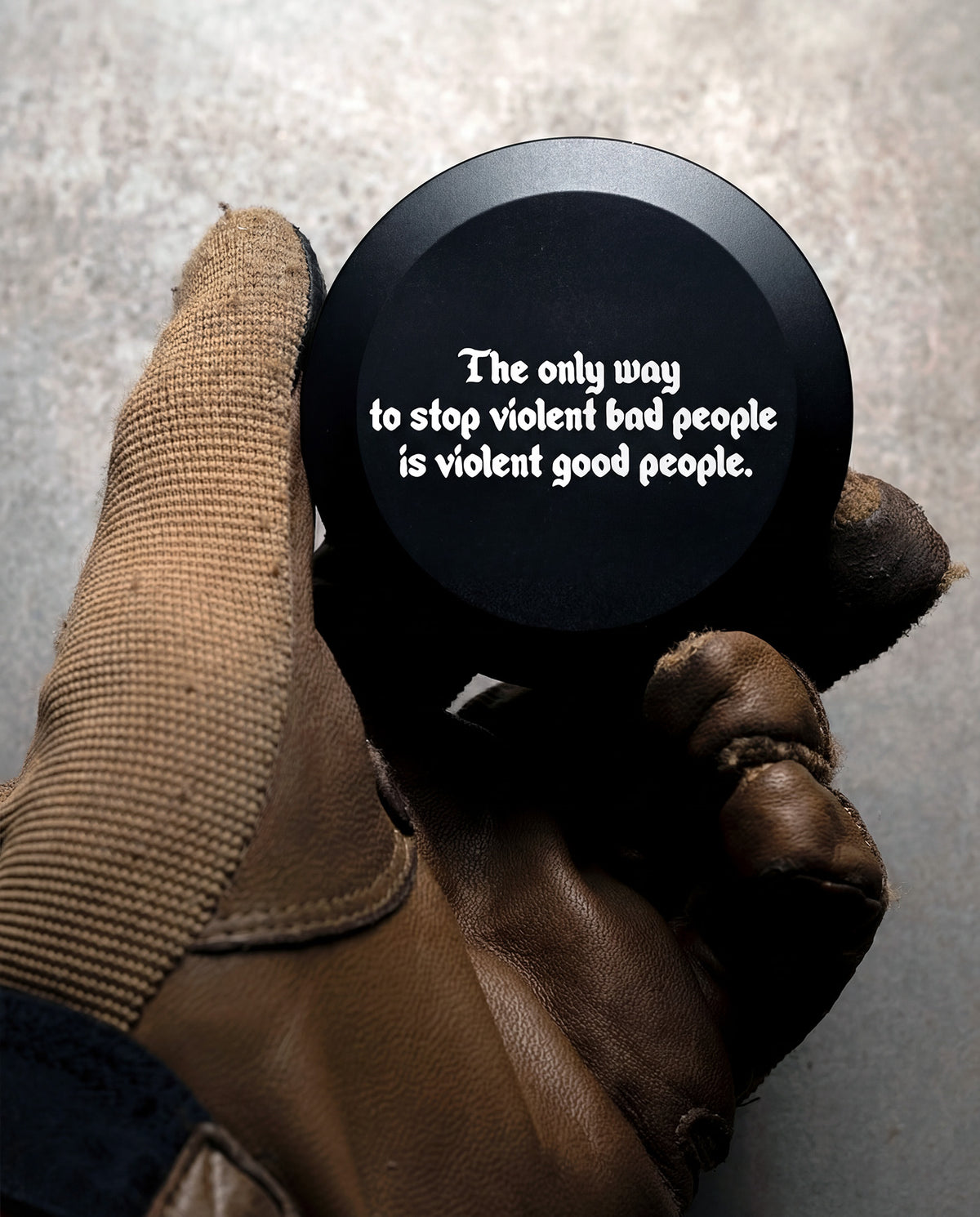 Black Stay Violent Pouch Can with the quote lettering on the lid, held in a brown glove