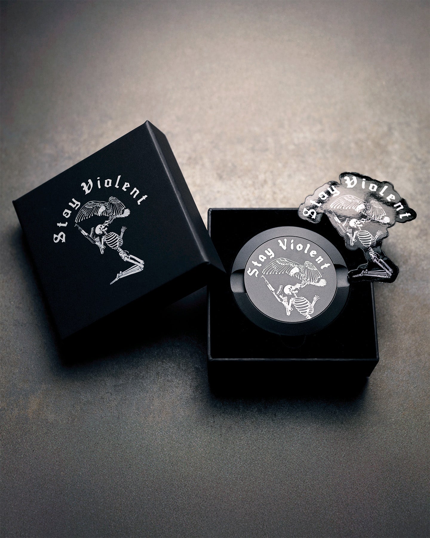 'Stay Violent' Pouch Can by Brothers in Arms in a black box on a gray surface