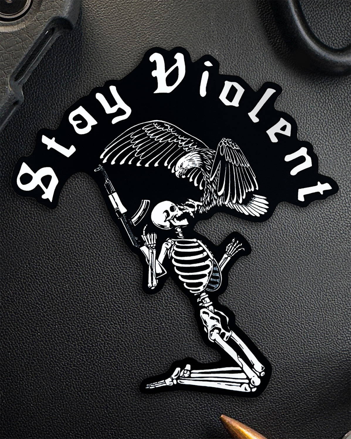 Single Stay Violent sticker with the skeleton artwork on a dark surface