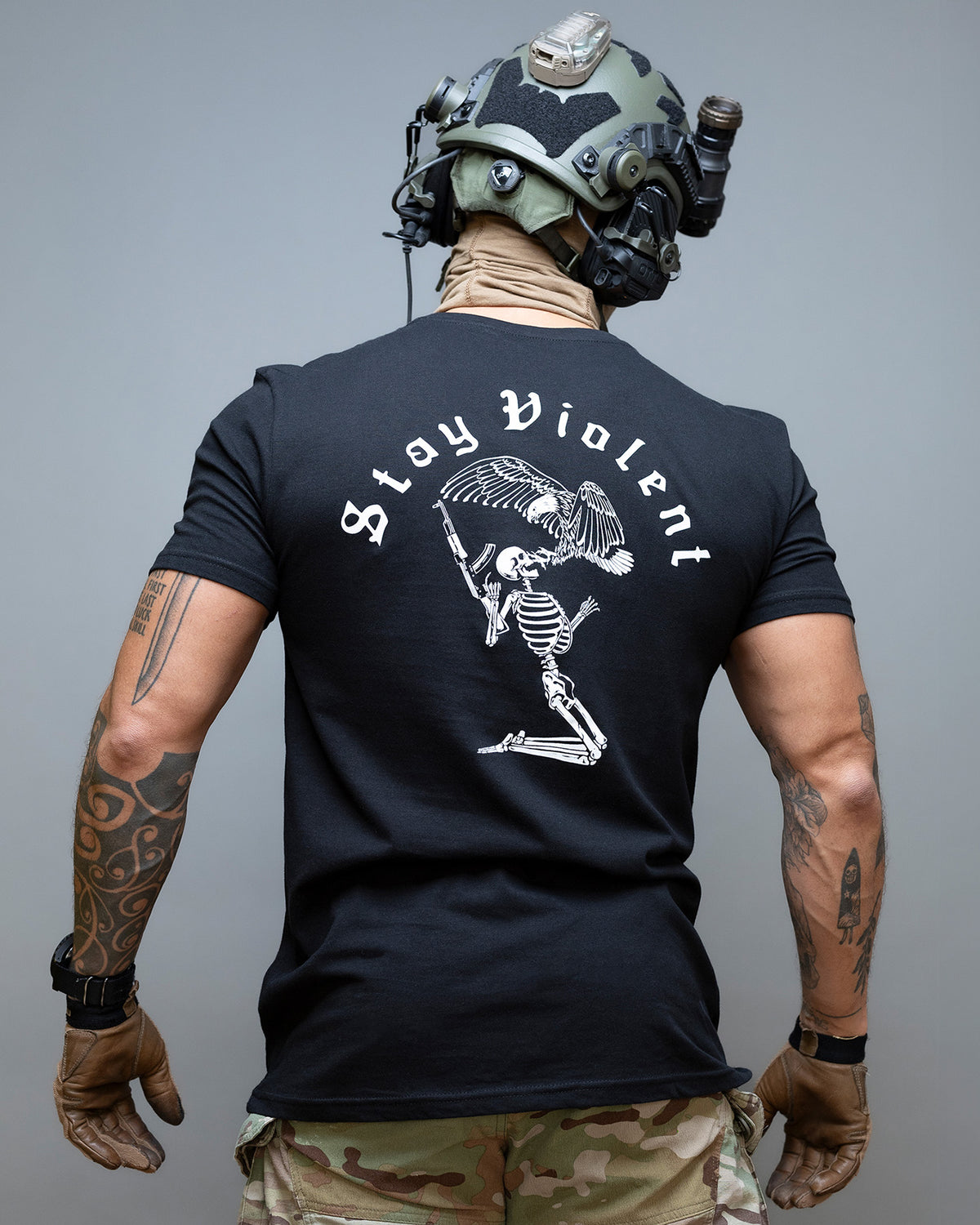 Man seen from behind in the black Stay Violent T-Shirt with the skeleton back print, wearing a helmet with night vision