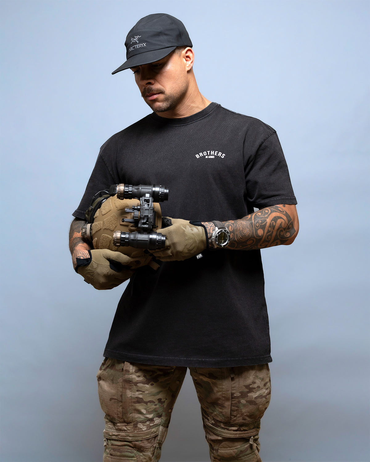 Man in a cap holding night vision, wearing the black Team Oversized Shirt